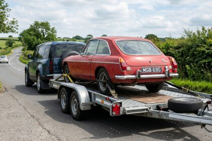 Enclosed tandem-axle car trailer transporting cargo behind a heavy-duty truck.
